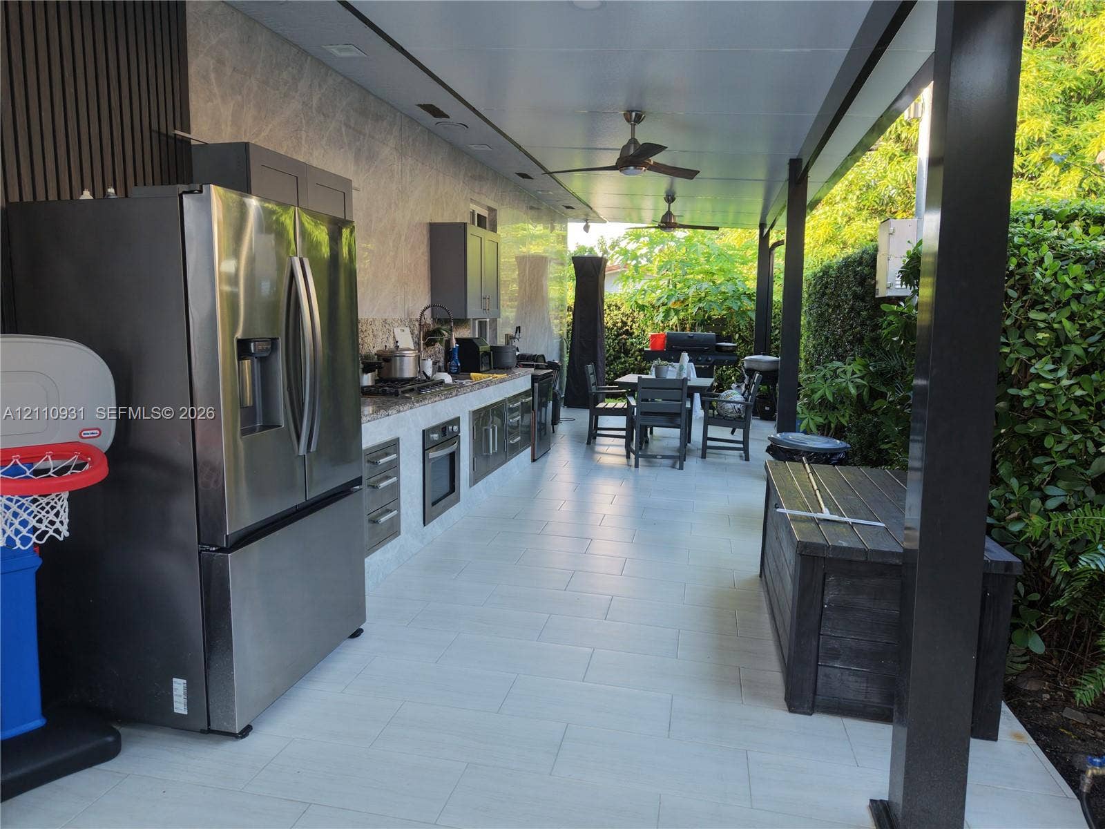 3005 SW 99th Court, Miami, FL 33165 Covered outdoor kitchen featuring tile flooring, stainless steel appliances, stone-finish backsplash, built-in cabinetry, and ceiling fans