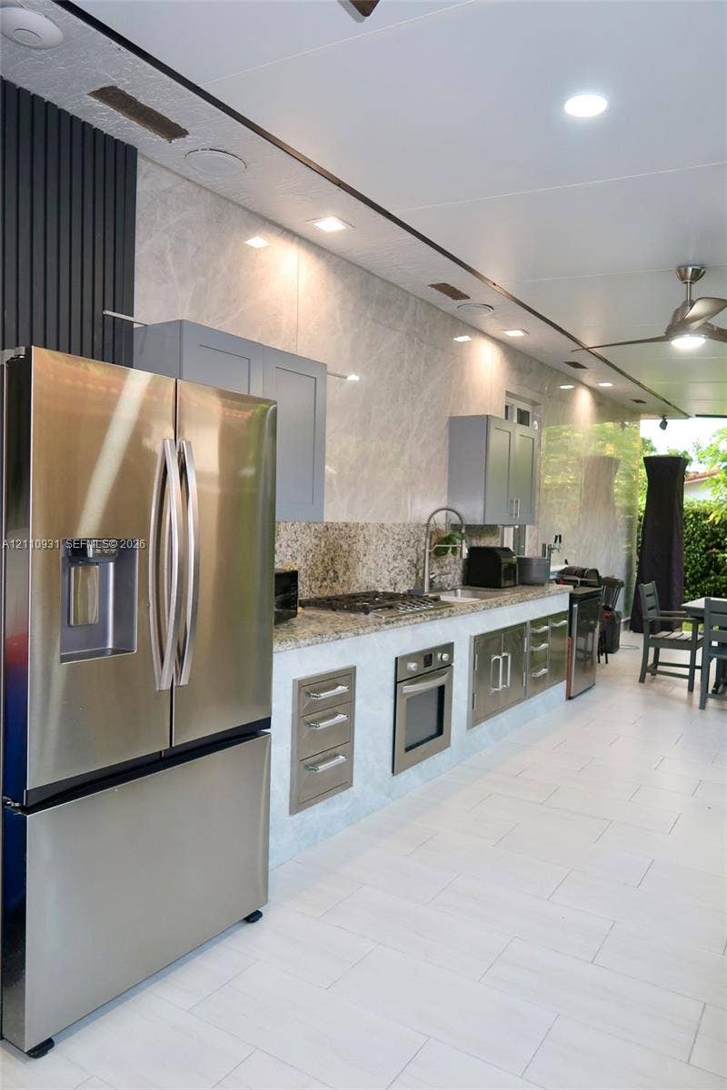 3005 SW 99th Court, Miami, FL 33165 Outdoor kitchen featuring stone countertops, stainless steel appliance suite, recessed lighting, tile flooring, and integrated cabinetry
