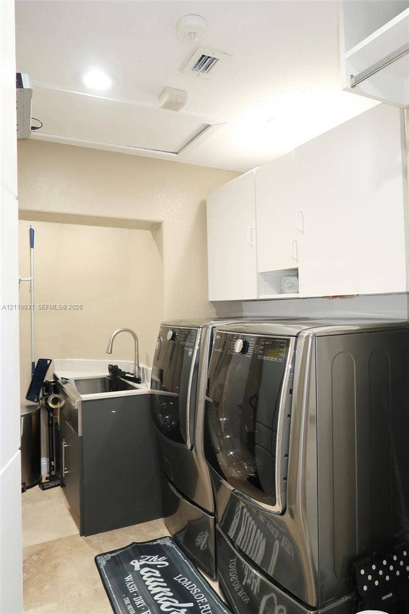 3005 SW 99th Court, Miami, FL 33165 Utility space featuring white overhead cabinetry, stone-finish countertops, an under-mount sink with a high-arch faucet, and neutral tile flooring