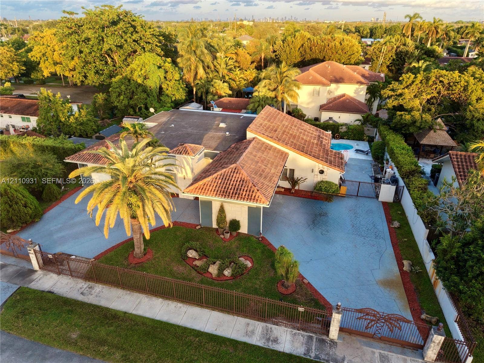 3005 SW 99th Court, Miami, FL 33165 Aerial perspective of a property featuring a tile roof, paved driveway, gated entry, mature landscaping, and an outdoor swimming pool