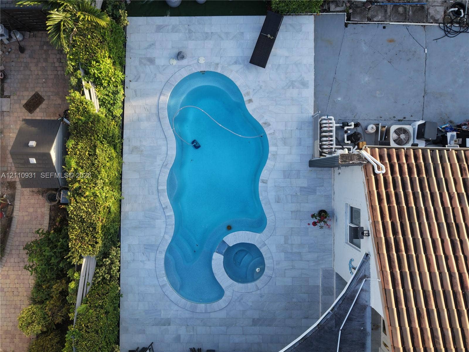 3005 SW 99th Court, Miami, FL 33165 Freeform swimming pool featuring an integrated spa, surrounded by stone-tile decking