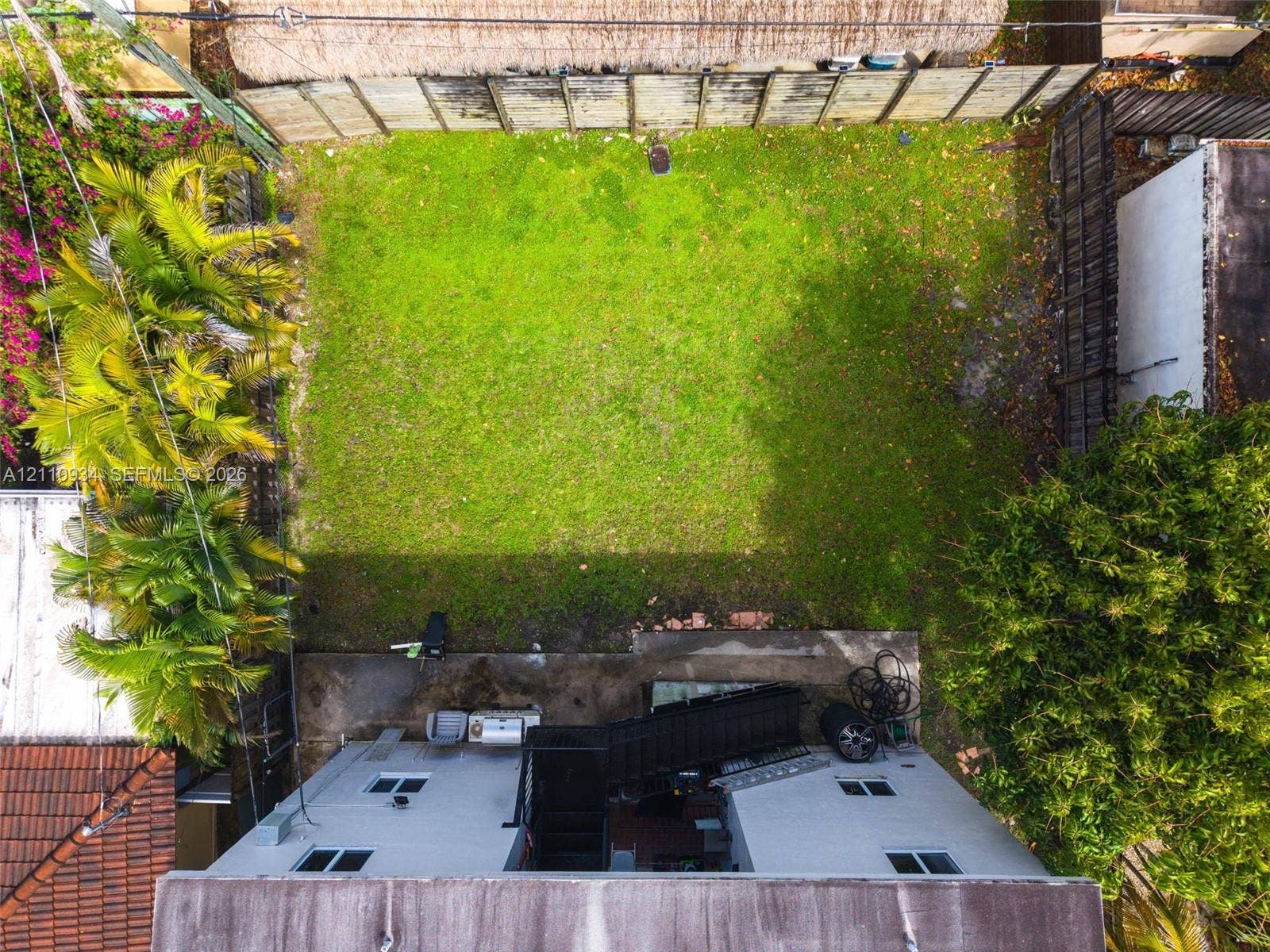 Backyard featuring a grass lawn, perimeter wood fencing, concrete patio, and mature landscaping