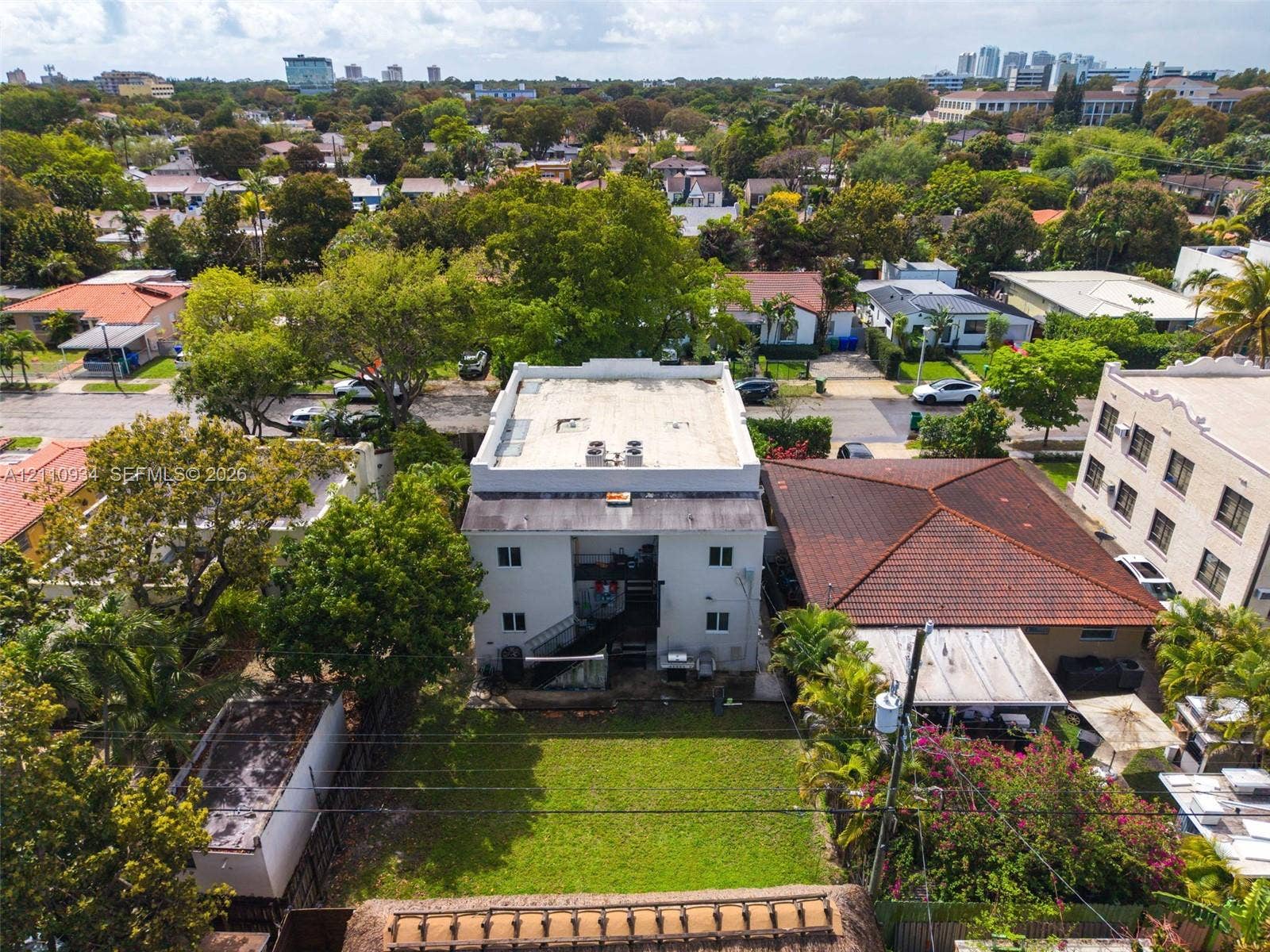 Aerial perspective of a multi-story building featuring a flat roof and a private rear lawn