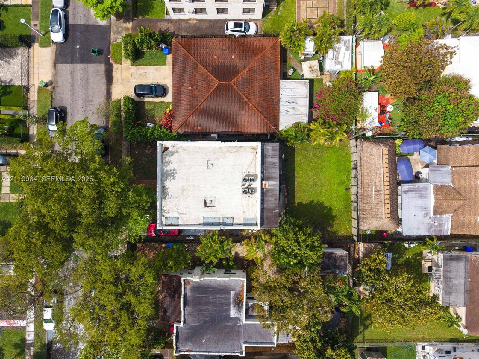 Aerial view of property featuring a flat roofline, integrated HVAC units, and a private grass-covered backyard
