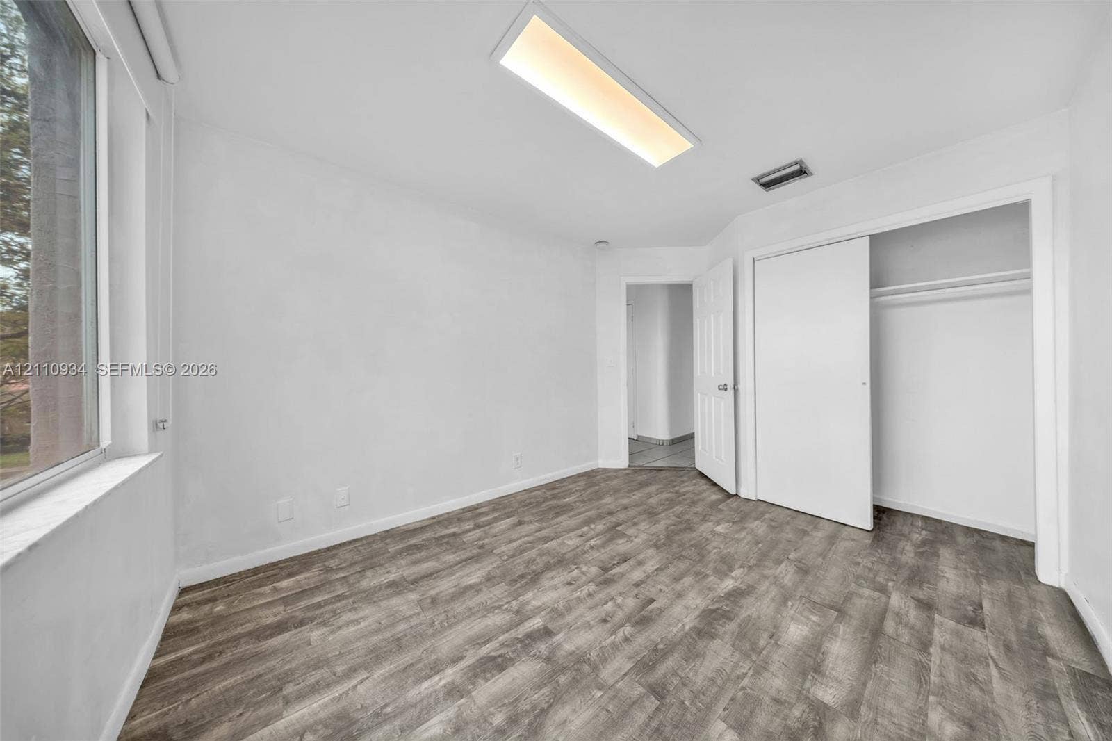 Room featuring wood-finish flooring, recessed rectangular ceiling lighting, and a closet with sliding doors