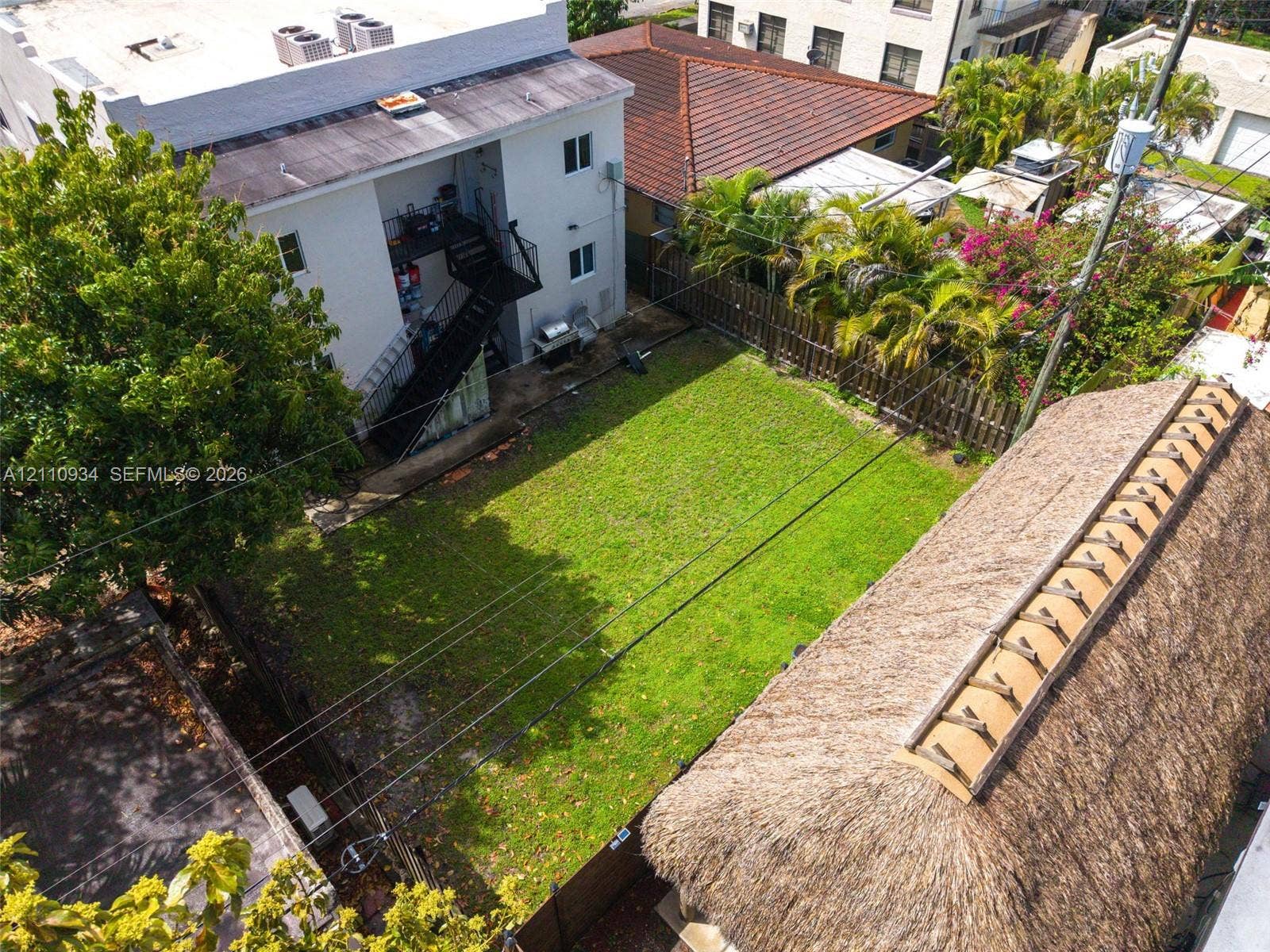 Open green space featuring a manicured lawn, perimeter wood fencing, and mature trees