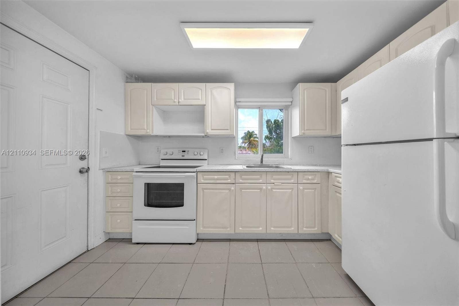 Kitchen featuring white cabinetry, tile flooring, a built-in white electric range, and a drop-in stainless steel sink