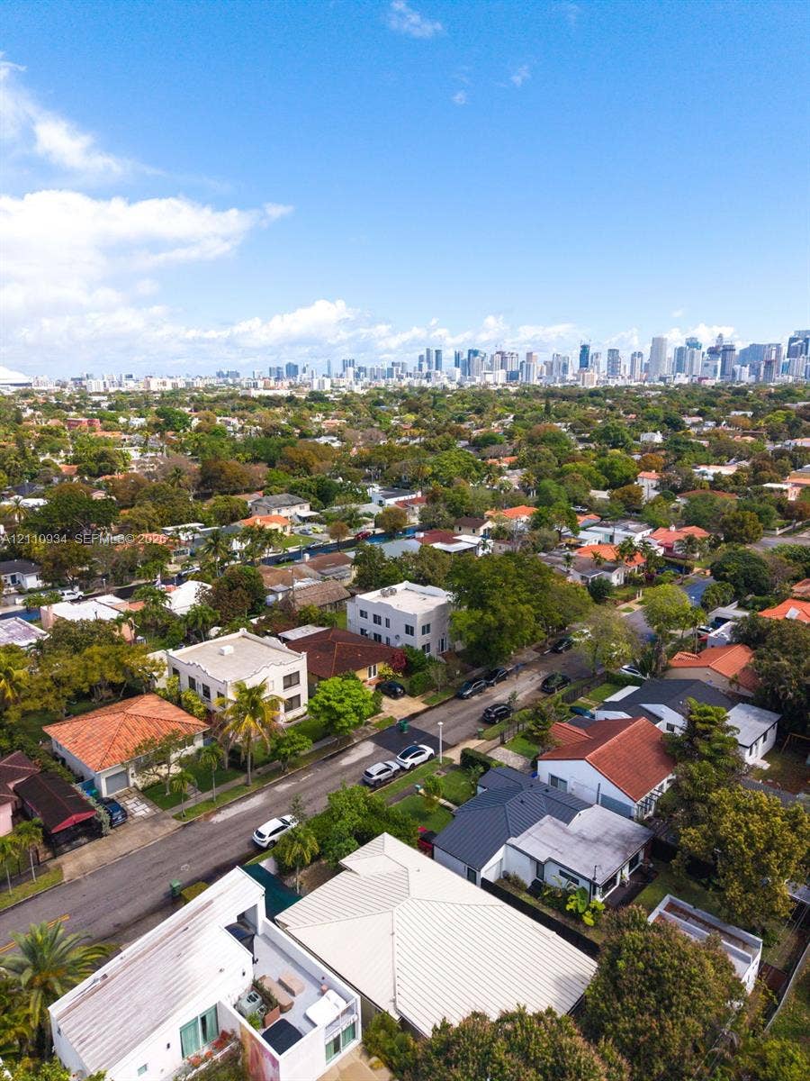 Aerial perspective showcasing an expansive urban skyline backdrop, mature canopy coverage, and established residential street infrastructure