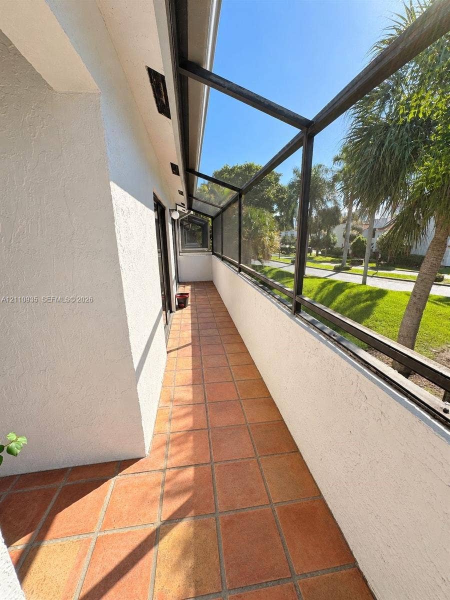 3530 Magellan Circle, #618, Aventura, FL 33180 Covered screened porch featuring terracotta tile flooring, stucco wall finish, and metal framing
