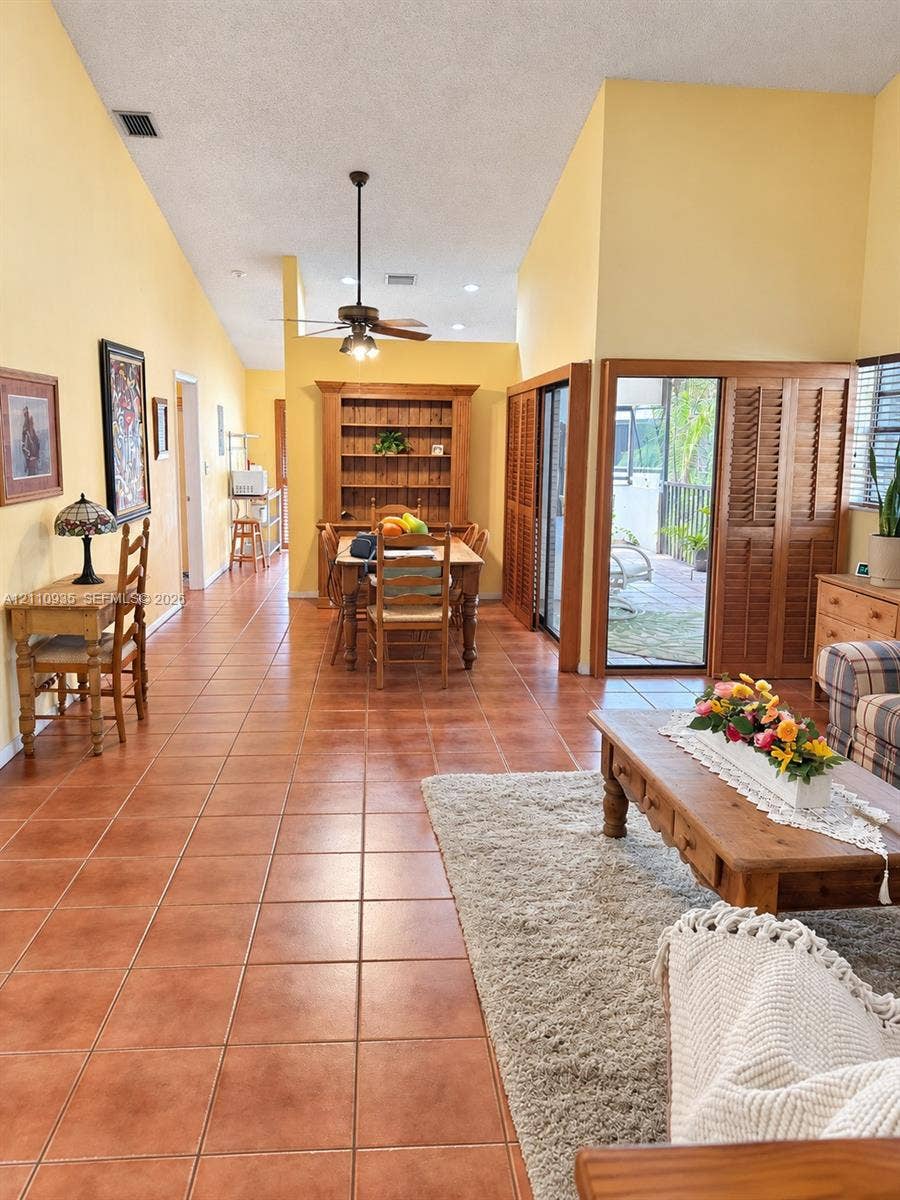 3530 Magellan Circle, #618, Aventura, FL 33180 Vaulted ceilings, ceramic tile flooring, built-in wooden shelving, and sliding glass doors with shutter-style privacy panels