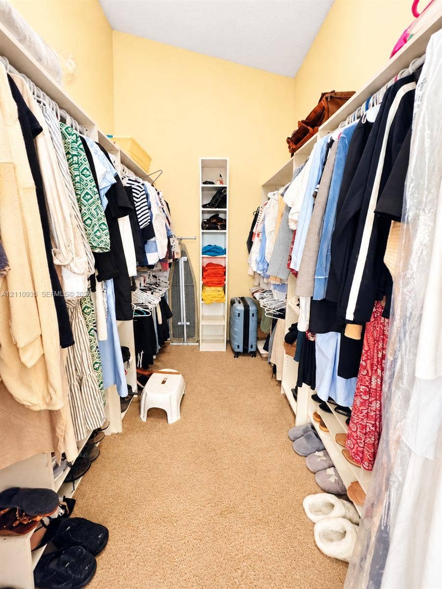 3530 Magellan Circle, #618, Aventura, FL 33180 Walk-in closet featuring extensive built-in white shelving, hanging rods, and a vertical multi-tier storage column