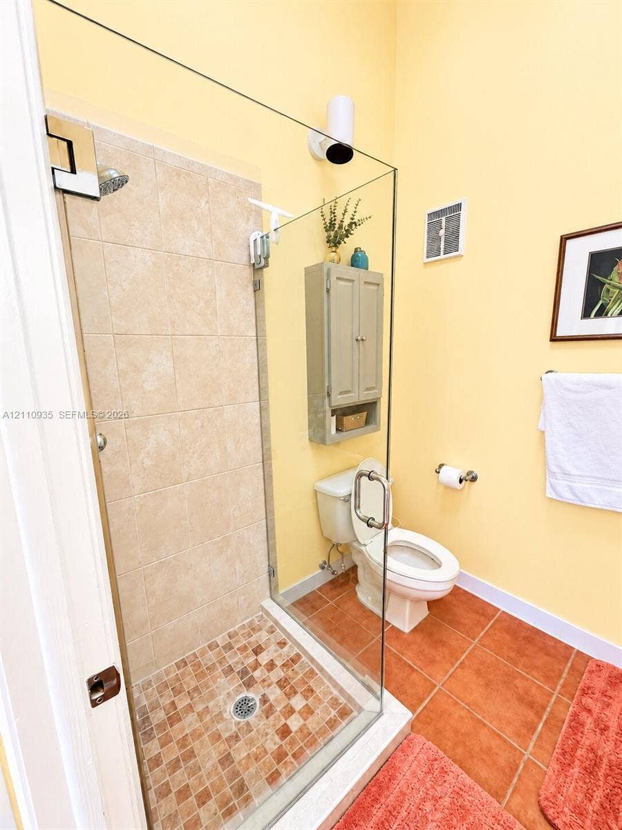 3530 Magellan Circle, #618, Aventura, FL 33180 Frameless glass shower enclosure with ceramic wall tile and mosaic floor tiling, accompanied by a wall-mounted storage cabinet