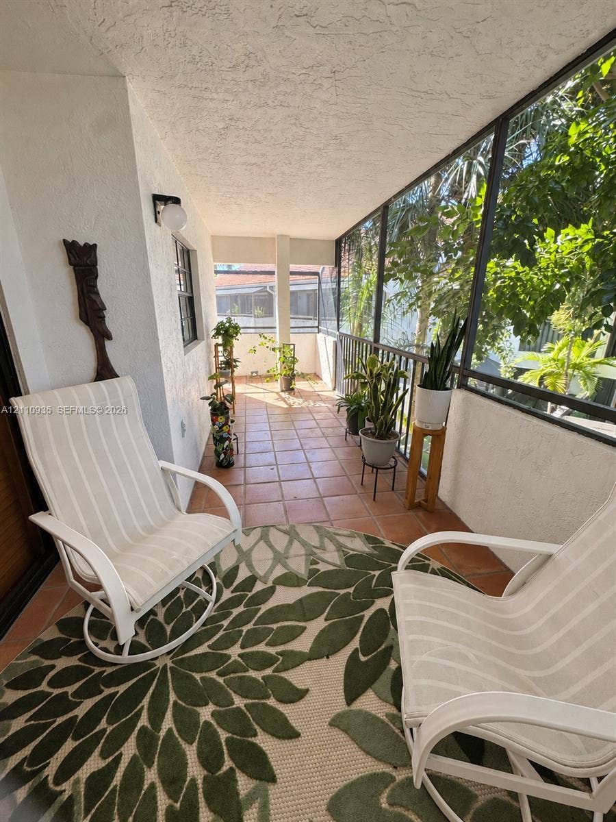 3530 Magellan Circle, #618, Aventura, FL 33180 Screened-in porch featuring ceramic tile flooring, metal railings, and a wall-mounted light fixture
