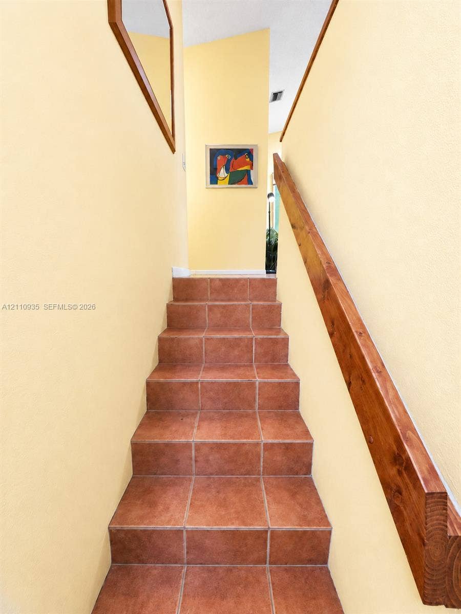 3530 Magellan Circle, #618, Aventura, FL 33180 Staircase featuring terracotta-style tile treads and a solid wood handrail