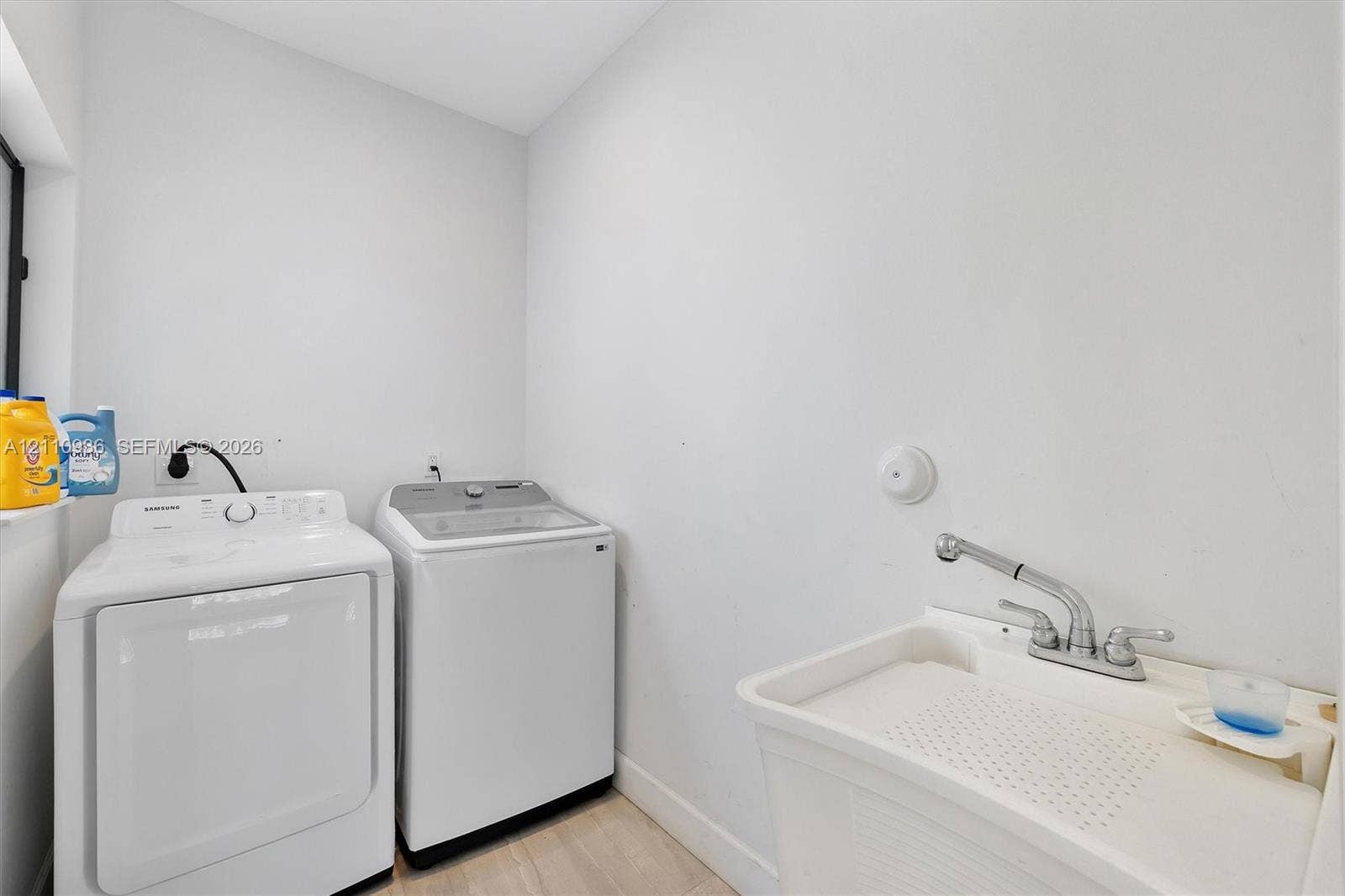 Utility space featuring a thermoplastic deep-basin sink, dual-handle faucet, and dedicated laundry hookups