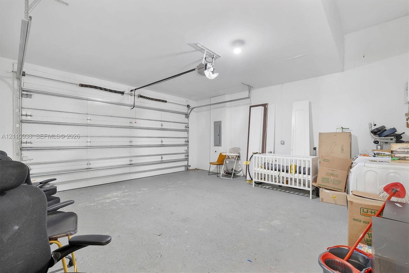 Two-car garage featuring a sectional overhead door, painted concrete flooring, and ceiling-mounted light fixture