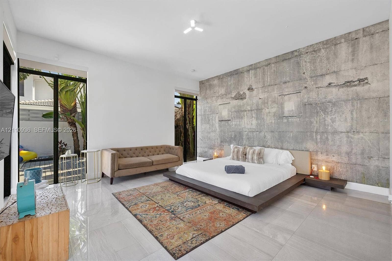Expansive room featuring a raw concrete accent wall, large-format tile flooring, and floor-to-ceiling glass sliding doors