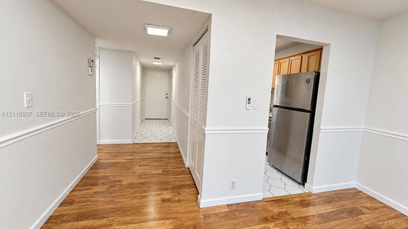 Interior featuring wood-finish flooring, white chair rail molding, louvered closet doors, and stainless steel refrigerator