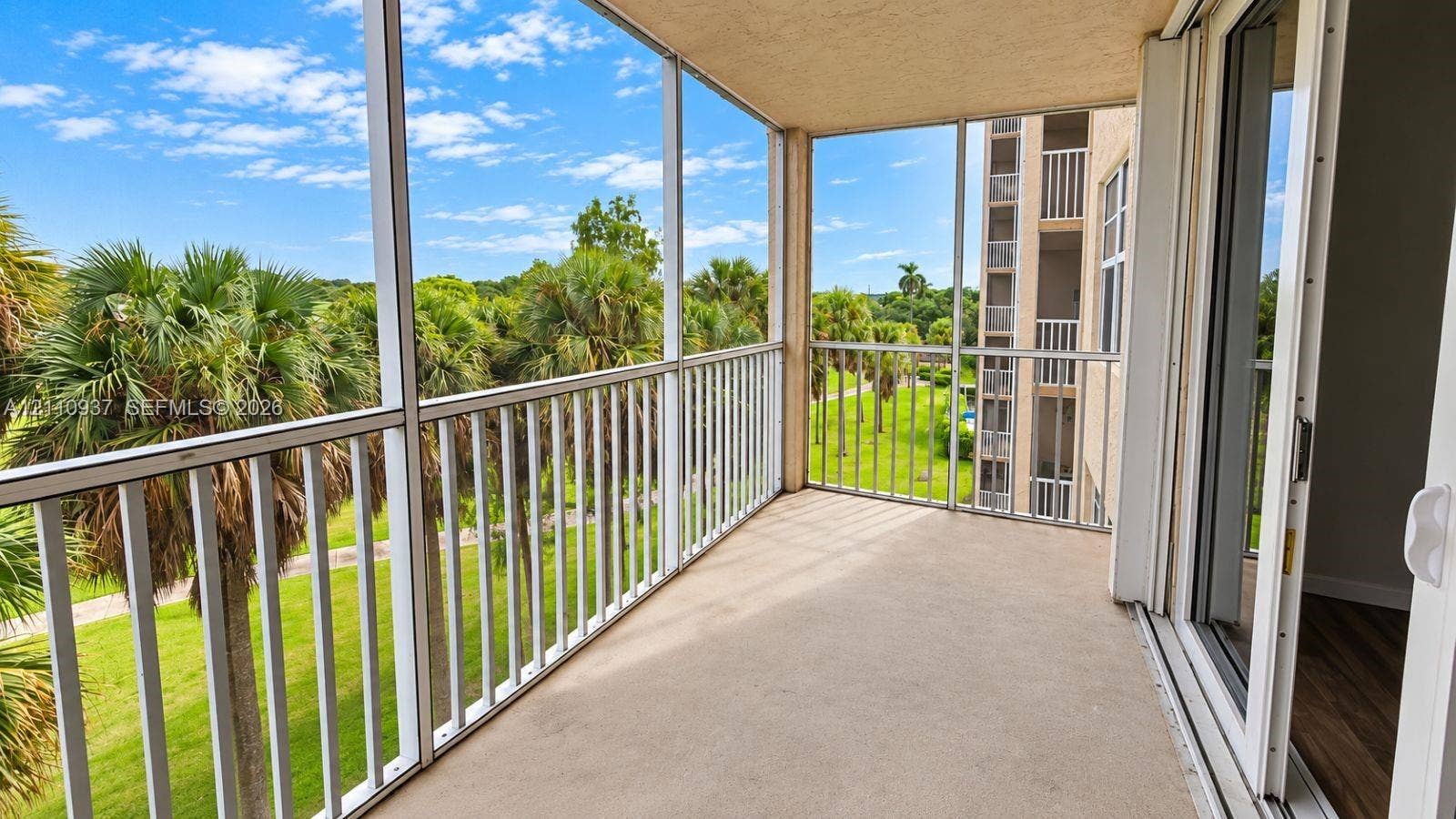 Screened-in balcony featuring white metal railings and concrete flooring