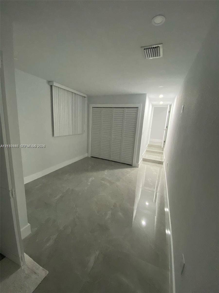 Interior space featuring high-gloss tile flooring, recessed ceiling lighting, and a closet with white louvered bifold doors