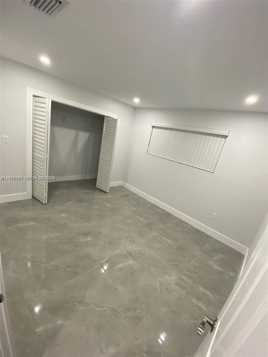 Room featuring high-gloss polished stone-style tile flooring, recessed ceiling lighting, and a bi-fold door closet