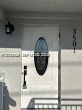 Entryway featuring a white door with an oval glass insert, vertical-mount house numbers, and a classic-style wall sconce