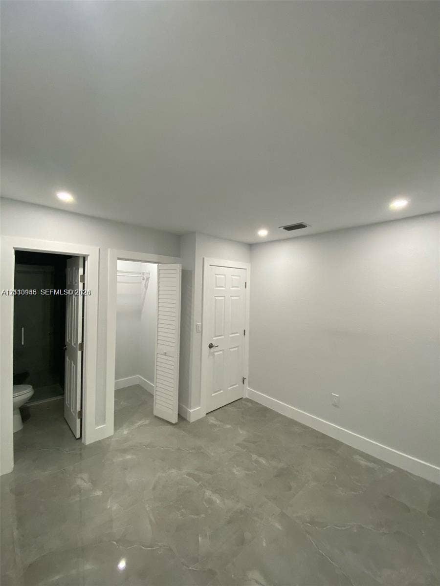 Polished large-format tile flooring, recessed ceiling lighting, louvered closet doors, and multi-panel interior doors