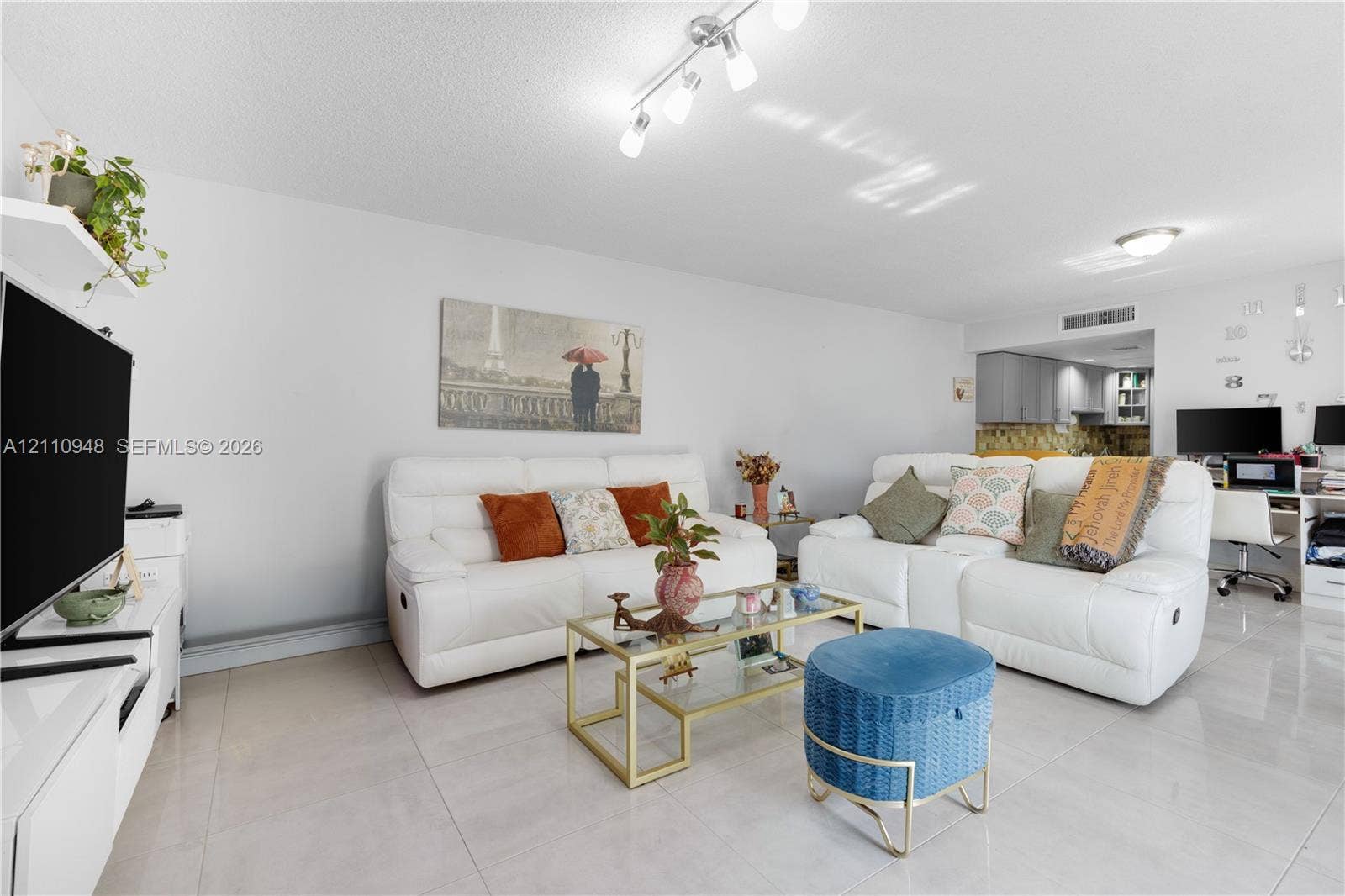Living area featuring polished tile flooring, multi-directional track lighting, and a neutral color palette