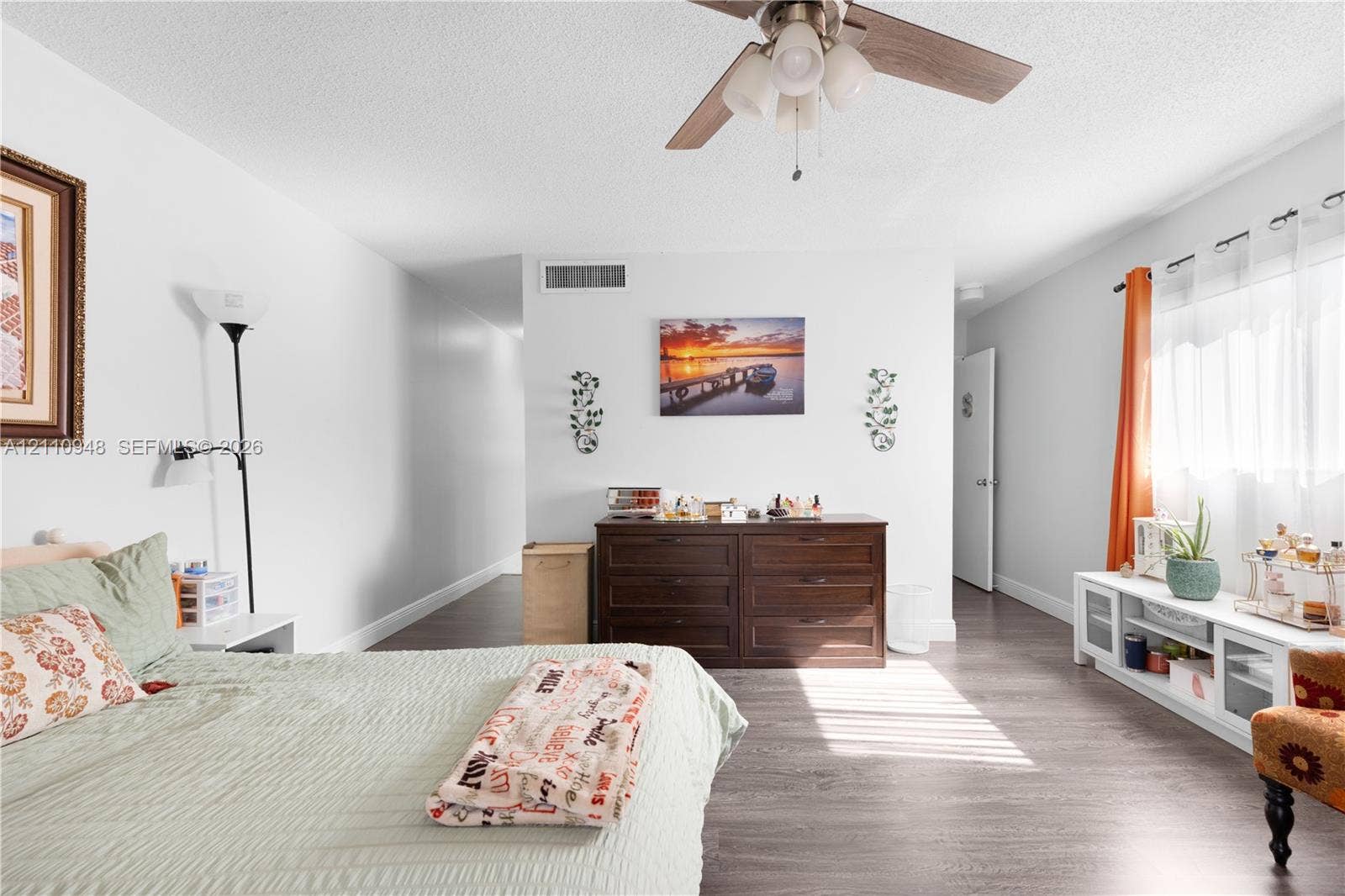Room featuring wood-finish flooring, a ceiling fan with integrated lighting, and white walls