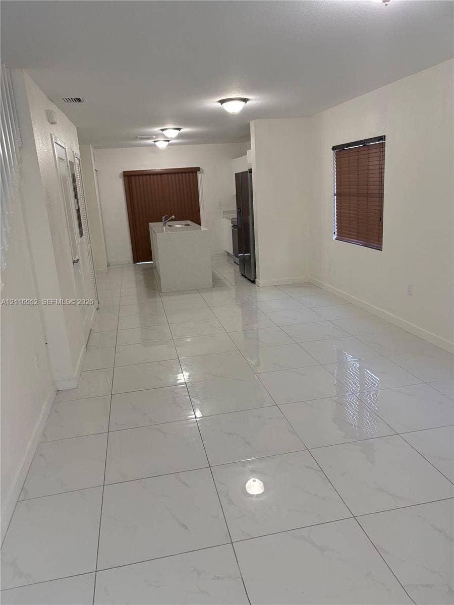 1225 NW 9 Avenue, #0, Florida City, Florida City, FL 33034 Large-format tile flooring with a light finish, central kitchen island with a built-in sink, stainless steel refrigerator, and recessed ceiling lighting