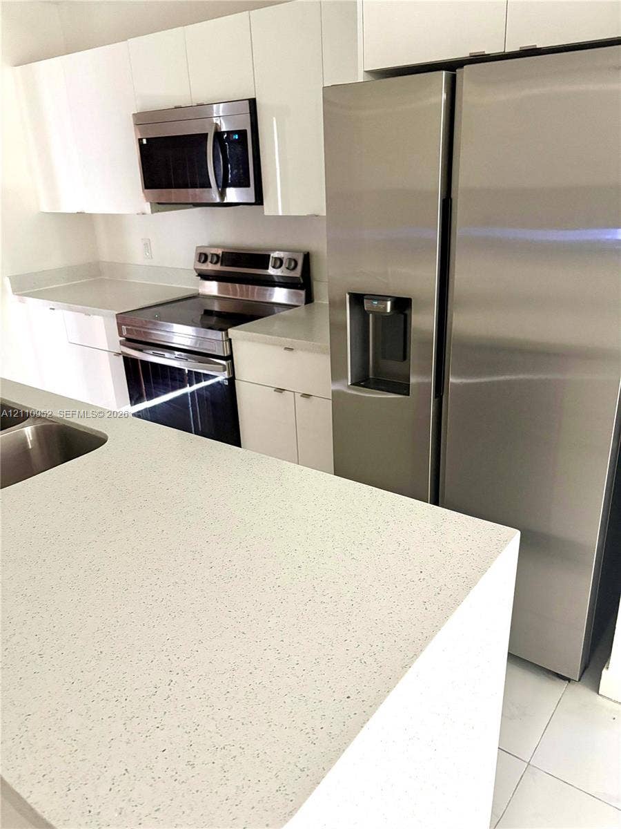 1225 NW 9 Avenue, #0, Florida City, Florida City, FL 33034 Kitchen featuring white flat-panel cabinetry, stone-finish countertops, stainless steel side-by-side refrigerator, matching stainless steel range, and built-in microwave