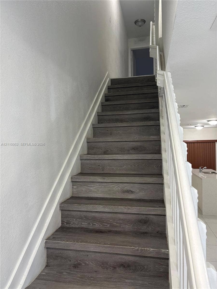 1225 NW 9 Avenue, #0, Florida City, Florida City, FL 33034 Staircase featuring wood-finish treads, a white handrail, white balusters, and recessed ceiling lighting