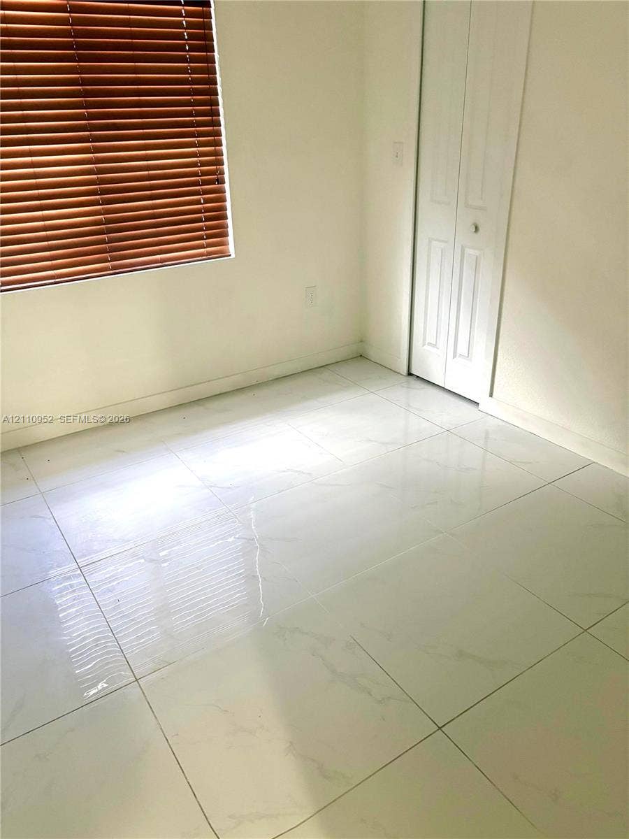 1225 NW 9 Avenue, #0, Florida City, Florida City, FL 33034 Polished stone-finish tile flooring, white bi-fold closet doors, and horizontal slat window blinds