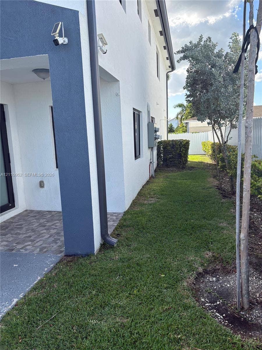 1225 NW 9 Avenue, #0, Florida City, Florida City, FL 33034 Stucco exterior side profile featuring a covered patio with patterned tile flooring, manicured lawn, and perimeter fence