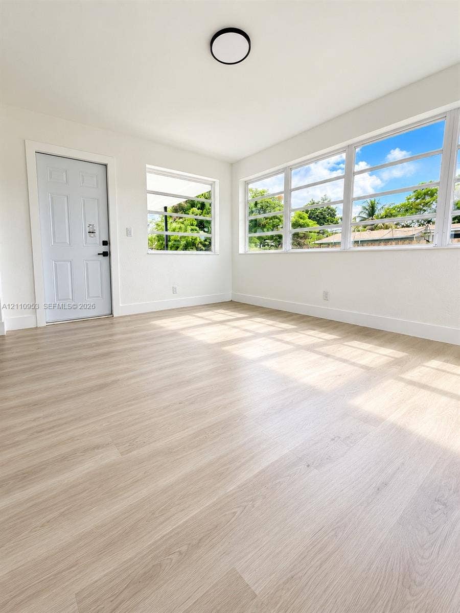 Neutral walls and wood-finish flooring, expansive horizontal sliding windows, and a flush-mount circular lighting fixture