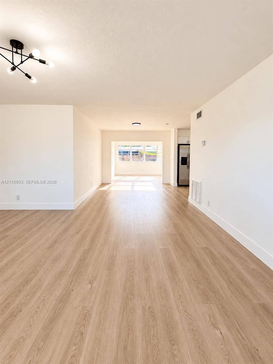Open floor plan featuring wood-finish flooring, neutral walls, and multi-arm geometric ceiling lighting