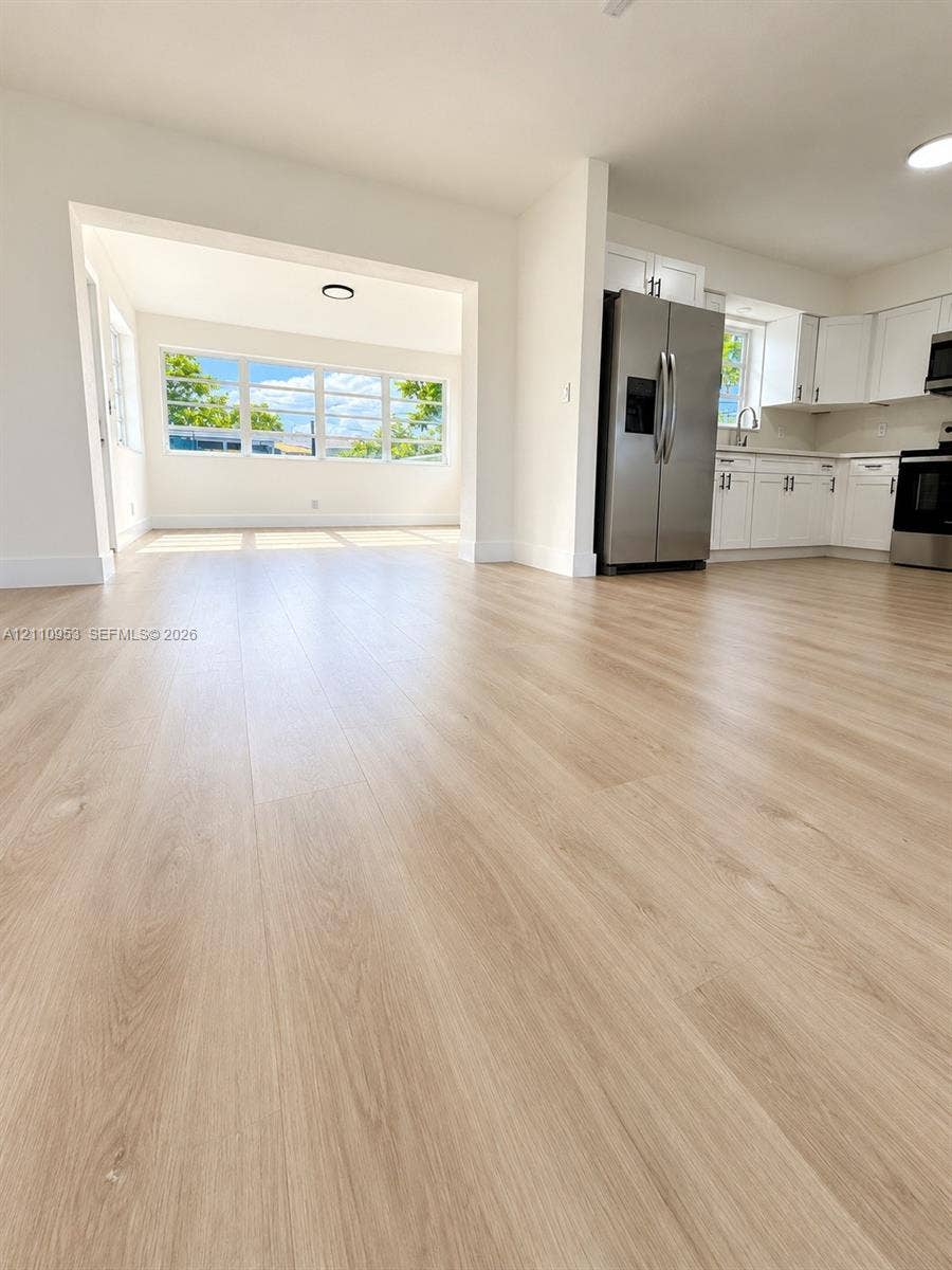 Wood-finish flooring, white shaker-style cabinetry, stainless steel appliances, and multi-pane windows