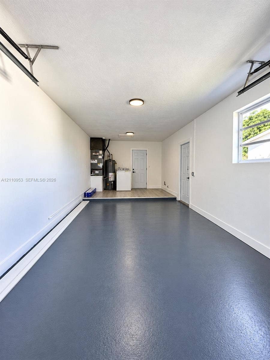 Attached two-car garage featuring sealed epoxy flooring, recessed ceiling lighting, and a window with horizontal panes