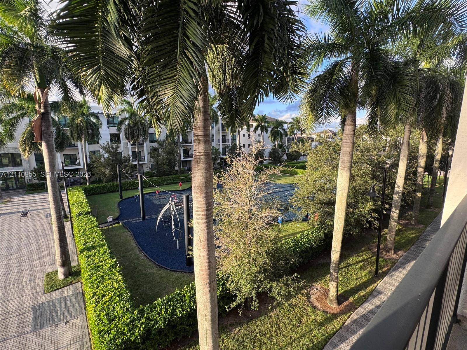 4636 NW 84th Avenue, #35, Doral, FL 33166 Outdoor recreation area featuring a rubberized surface, manicured hedges, mature palm trees, and paved walkways