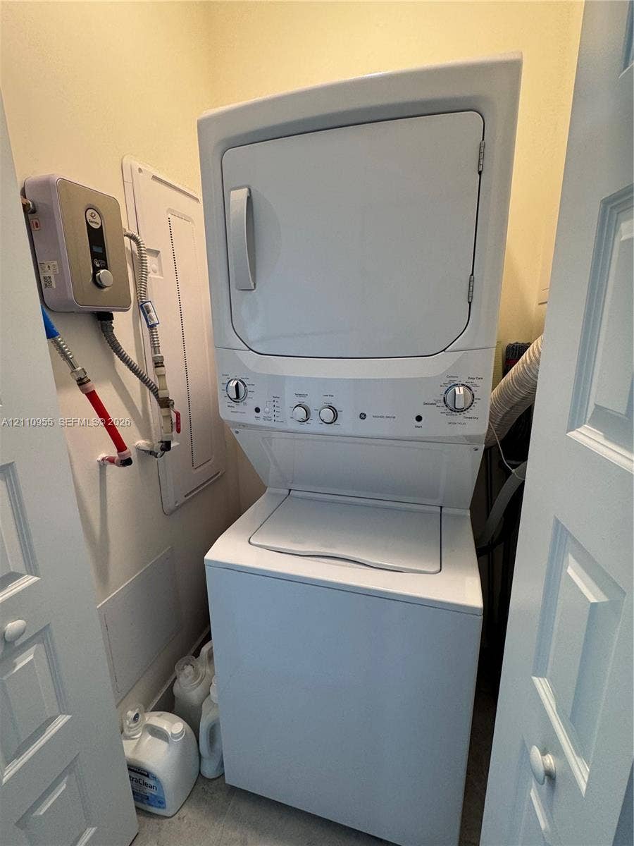 4636 NW 84th Avenue, #35, Doral, FL 33166 Stacked white laundry appliance center featuring a top-load washer, front-load dryer, and wall-mounted electric tankless water heater