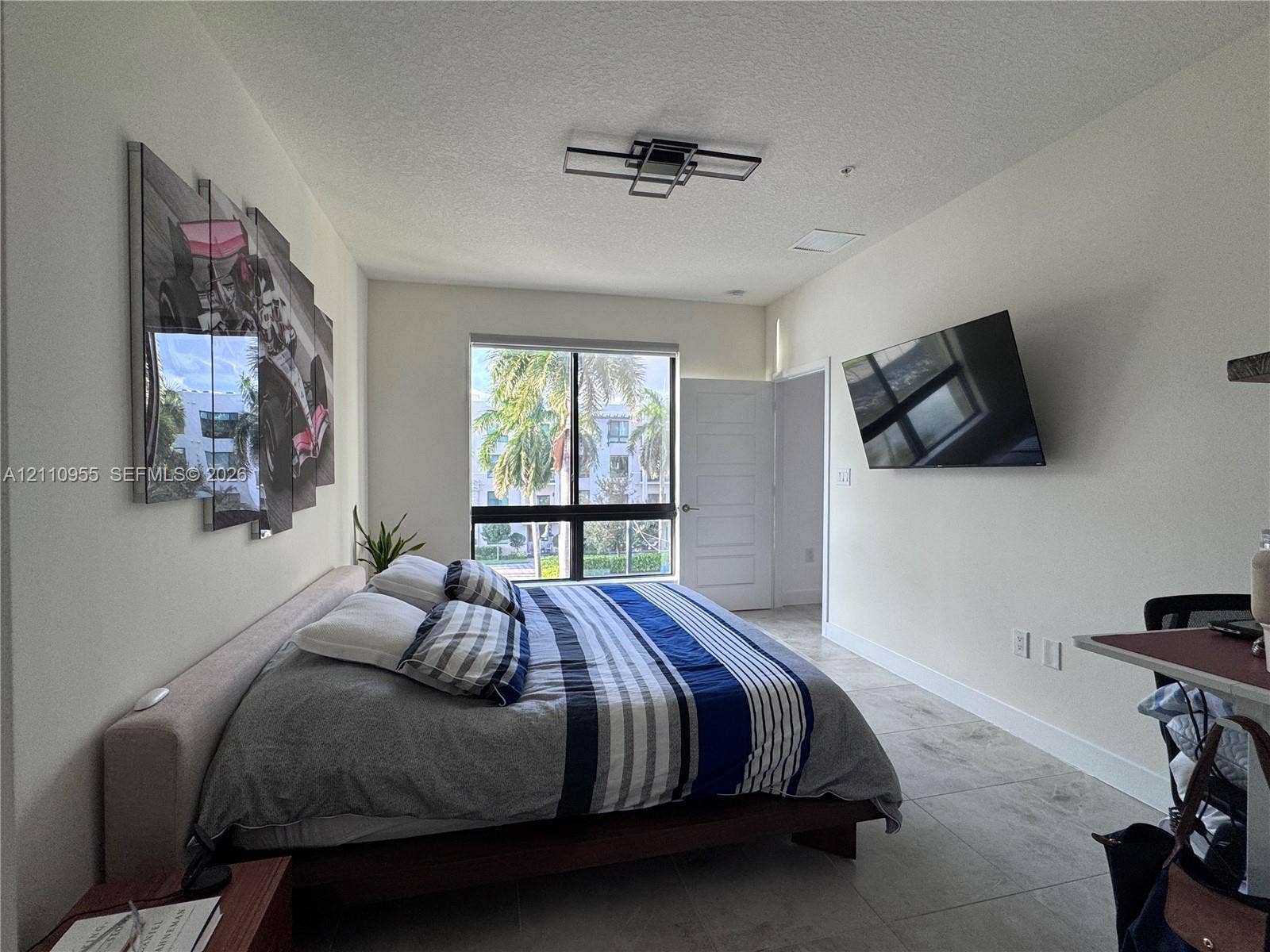 4636 NW 84th Avenue, #35, Doral, FL 33166 Large format tile flooring, contemporary geometric ceiling light fixture, and floor-to-ceiling window framing exterior landscape