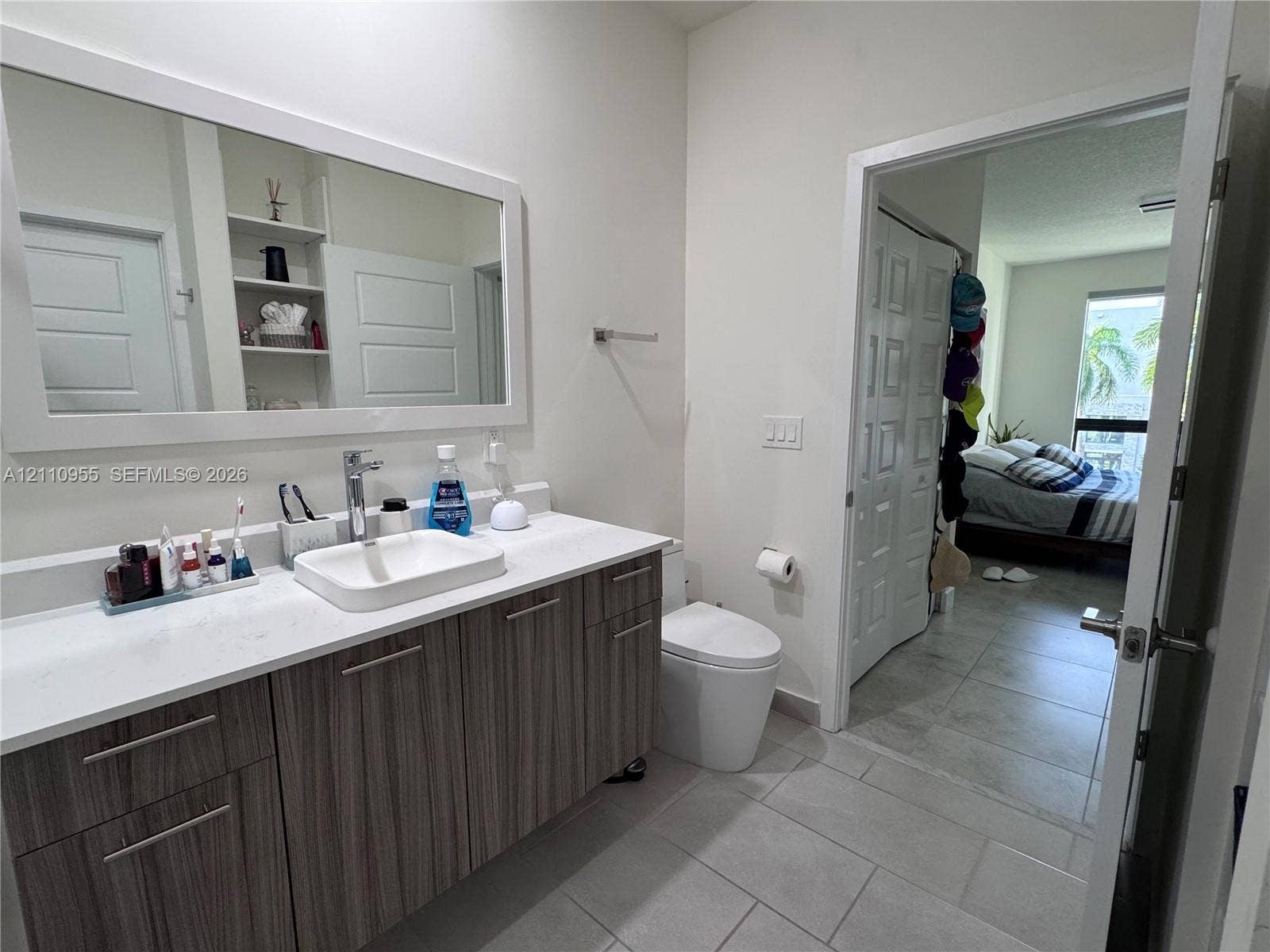 4636 NW 84th Avenue, #35, Doral, FL 33166 Bathroom featuring a wood-finish vanity with a stone countertop, an integrated rectangular vessel sink, a large framed mirror, and tile flooring