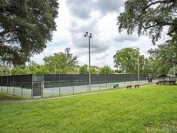 2120 SW 94th Terrace, #404, Davie, FL 33324 Tennis court facility enclosed by perimeter fencing, featuring integrated court lighting and a covered pavilion