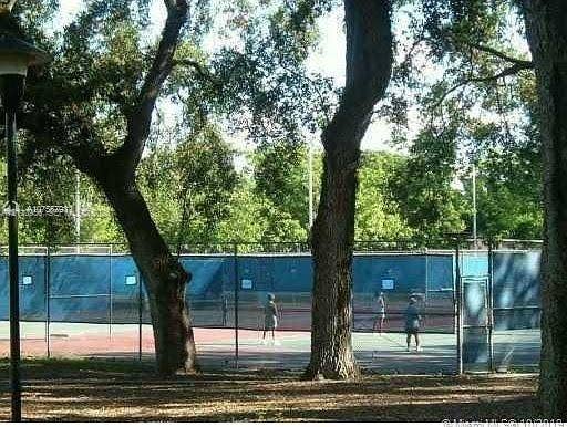 2120 SW 94th Terrace, #404, Davie, FL 33324 Tennis court enclosed with chain-link fencing, situated within a setting of mature trees