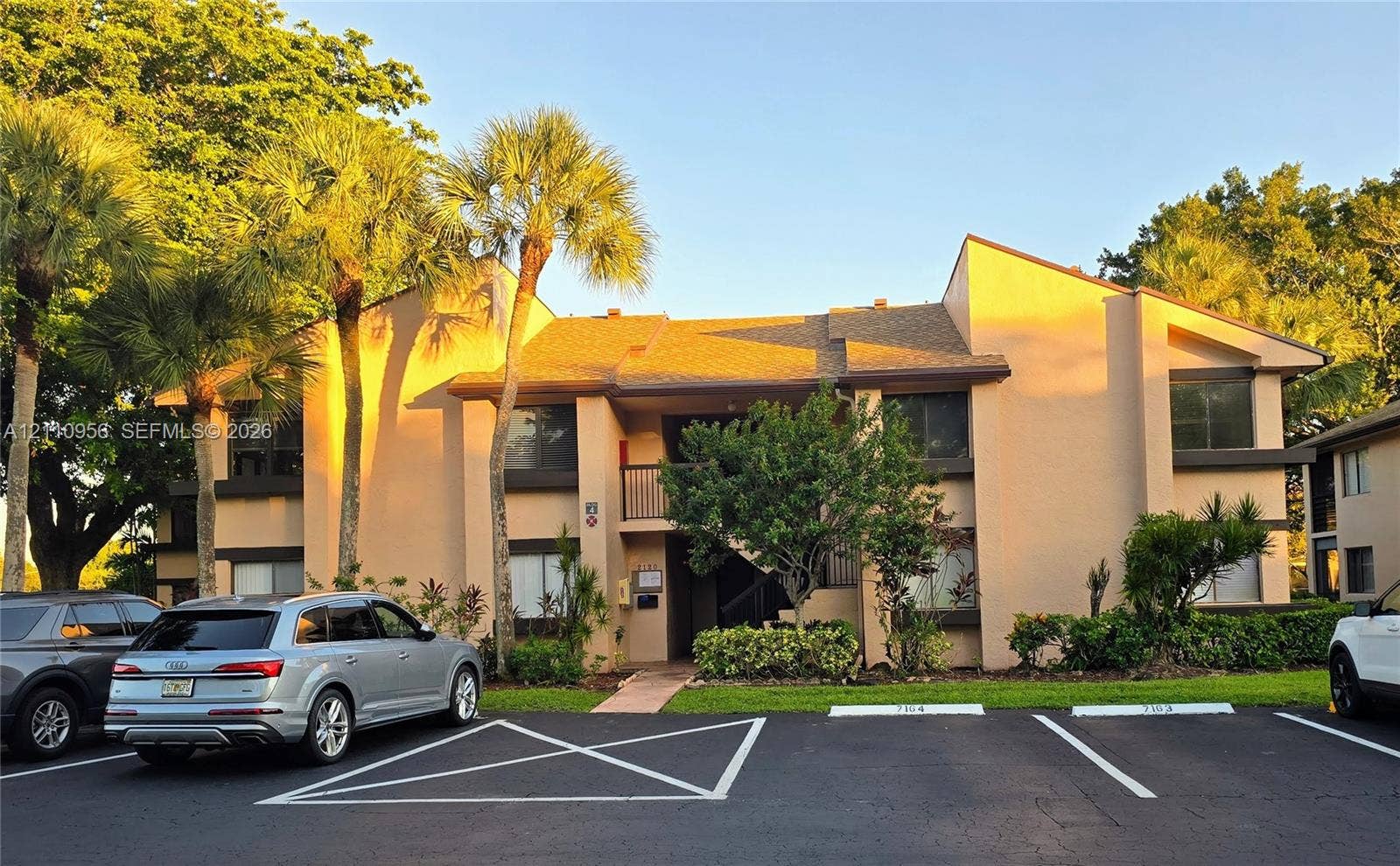 2120 SW 94th Terrace, #404, Davie, FL 33324 Two-story exterior featuring a textured stucco facade, asphalt shingle roof, integrated balconies, and mature palm tree landscaping