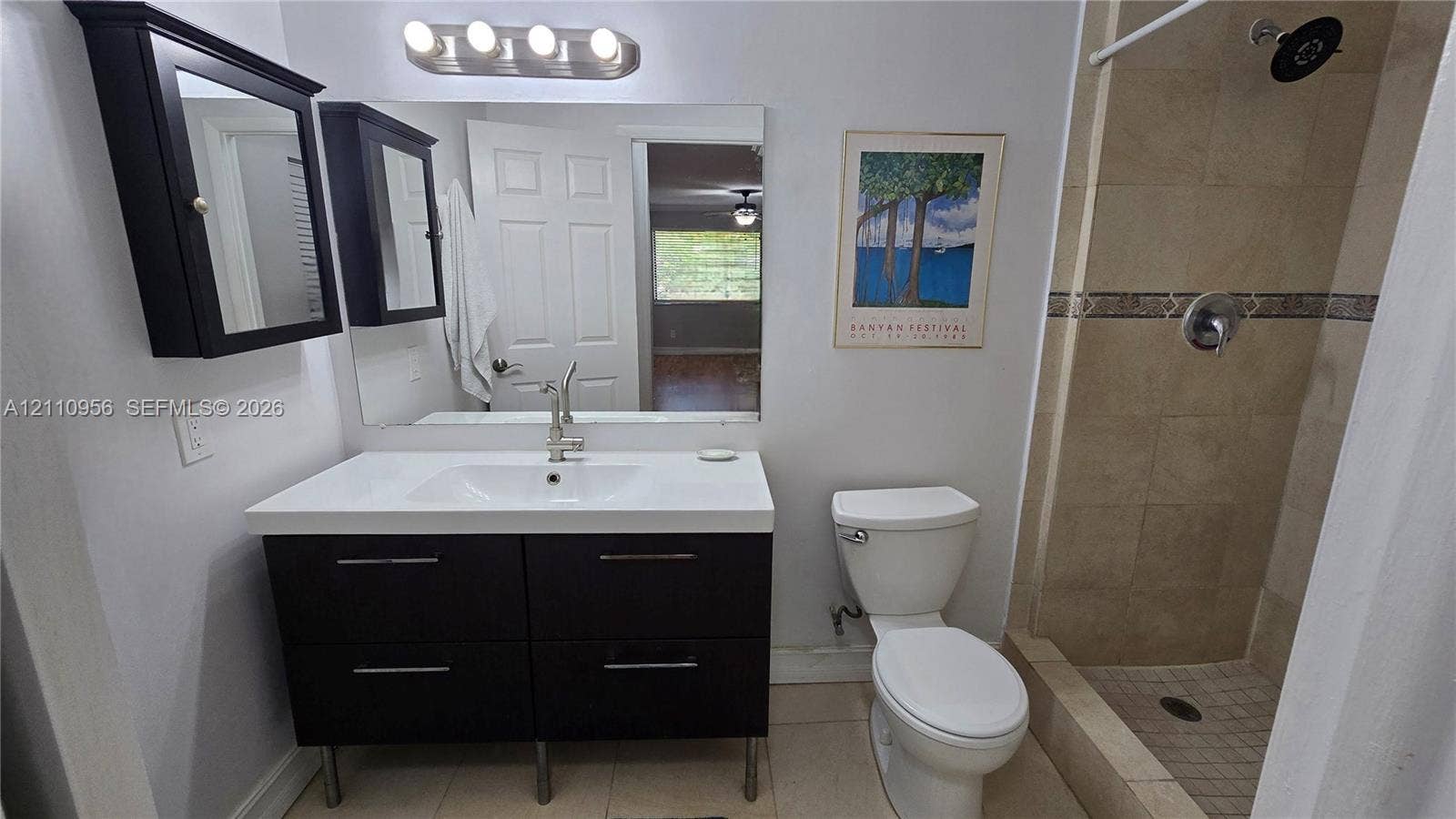 2120 SW 94th Terrace, #404, Davie, FL 33324 Bathroom featuring a modern floating vanity with a white countertop and rectangular basin, a wall-mounted mirrored medicine cabinet, a four-bulb light fixture, and a tile-surround shower with a metallic rain shower head