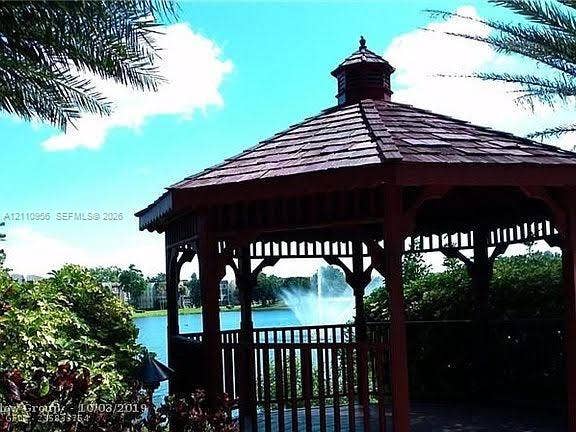 2120 SW 94th Terrace, #404, Davie, FL 33324 Octagonal wood-framed gazebo featuring a tiered roof with wood-shingle detailing, perimeter railing, and a waterfront location with a fountain