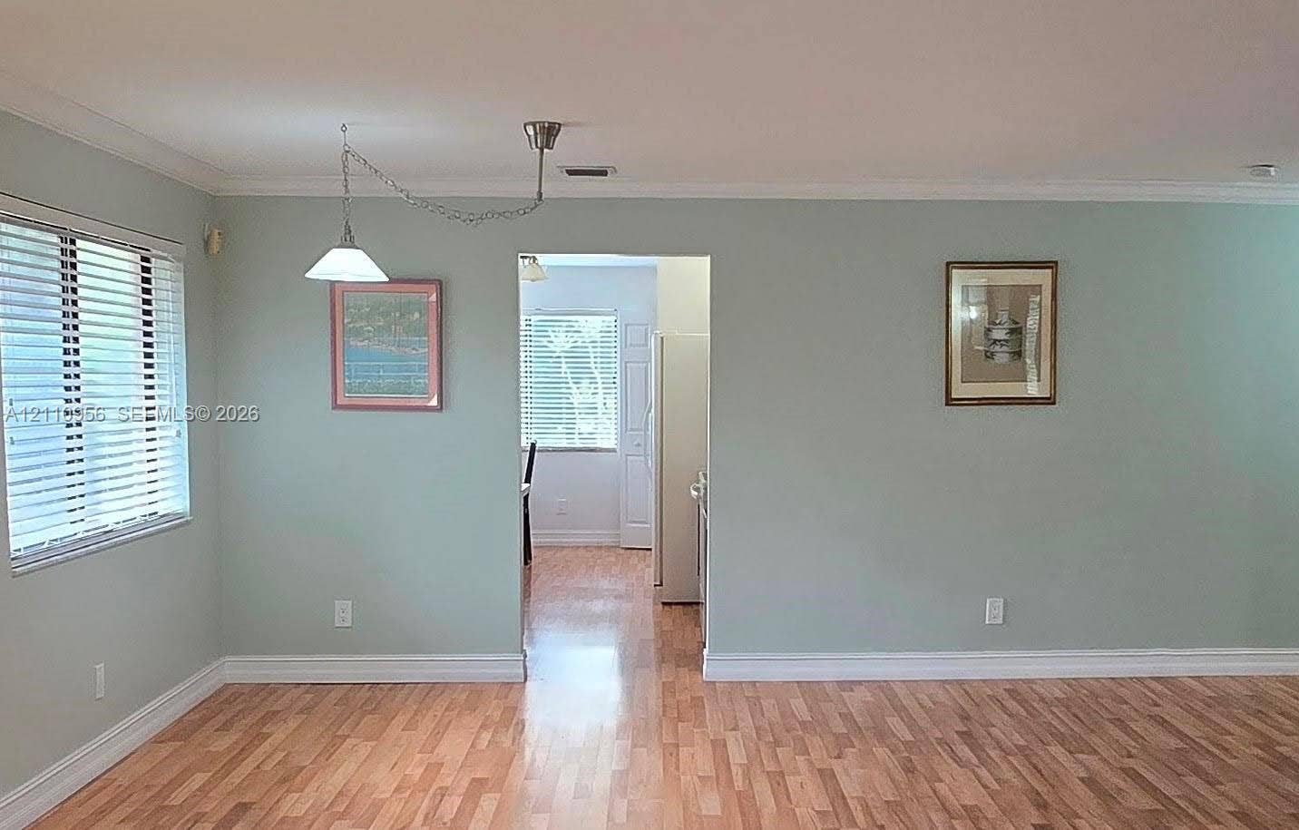 2120 SW 94th Terrace, #404, Davie, FL 33324 Interior space featuring wood-finish flooring, crown molding, and a suspended cone pendant light fixture