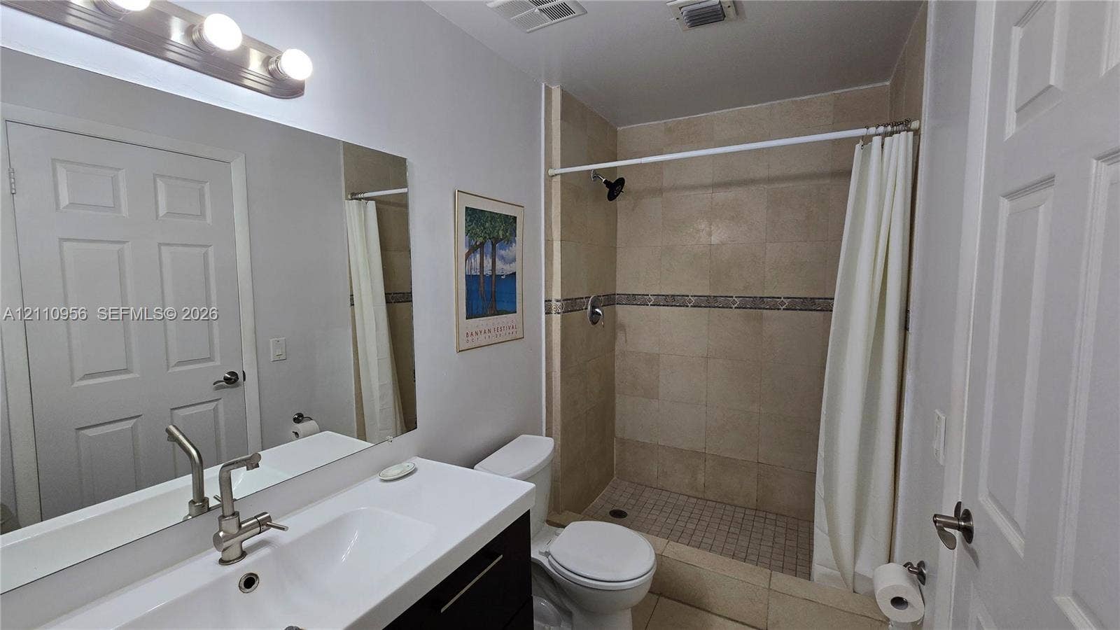 2120 SW 94th Terrace, #404, Davie, FL 33324 Bathroom featuring a dark wood-finish vanity, white integrated sink, rectangular wall mirror, and walk-in shower with stone-finish wall tiles
