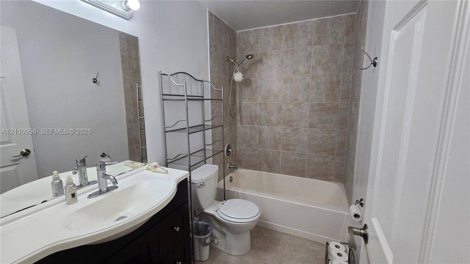 2120 SW 94th Terrace, #404, Davie, FL 33324 Bathroom featuring a vanity with an integrated basin, a polished metal faucet, a large wall-mounted mirror, a tub-shower combination with tile surround, and a neutral-toned toilet
